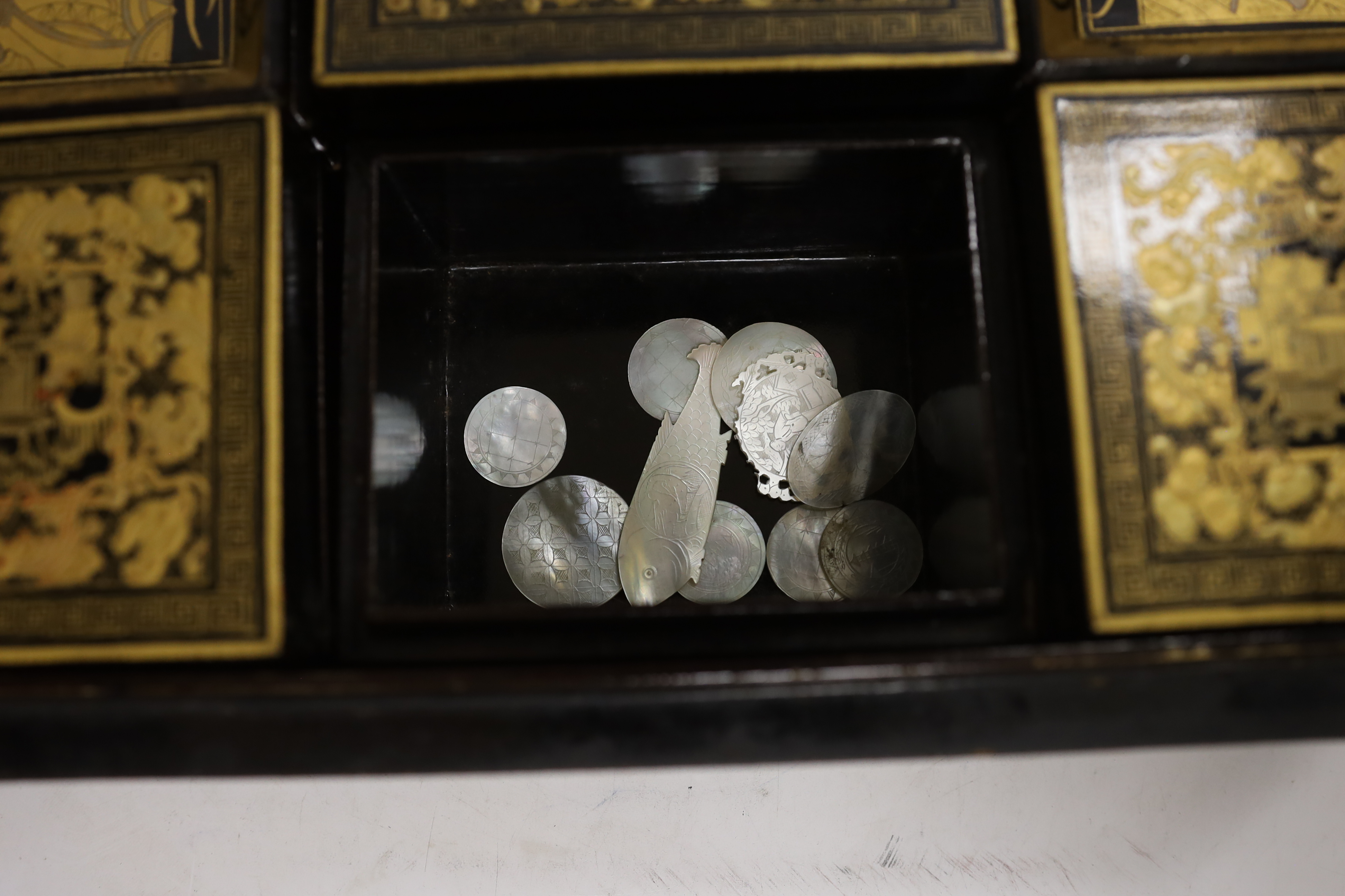 A mid 19th century Chinese gilt-decorated black lacquer games box containing mother-of-pearl counters